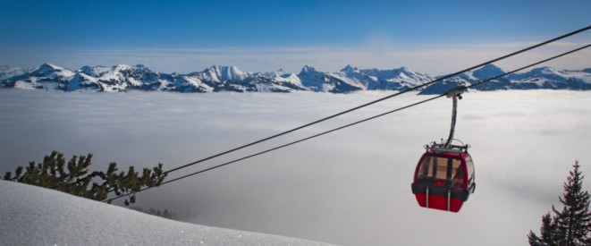 Schneegarantie: Welche Rechte haben Winterurlauber? Die Gondel einer Seilbahn schwebt über Wolken verhangenen Bergen.