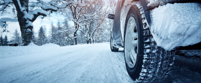 Winterdienst: Außerorts keine flächendeckende Streupflicht. Der Hinterreifen eines Autos auf einer schneebedeckten Straße.