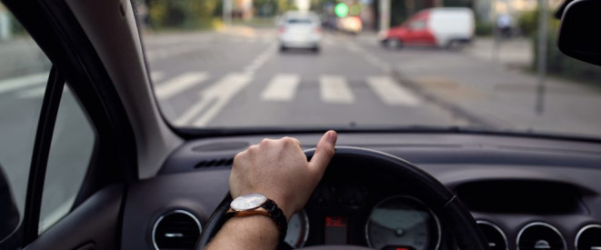 8 Punkte in Flensburg: Wann der Führerschein weg ist. Eine Person sitzt hinter dem Steuer eines Autos, der Blick ist auf die Straße gerichtet.