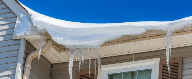 Dachlawine: Haftet der Hausbesitzer für Schäden? An einer Dachkante hängen Schnee und Eiszapfen herunter.