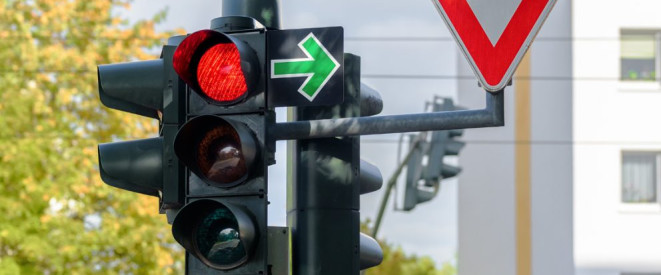 Grüner Pfeil an der Ampel: Was er bedeutet. Eine rote Ampel an deren rechter Seite ein grüner Pfeil und ein 