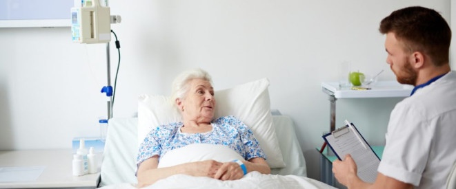 Pflegestärkungsgesetz III: Die wichtigsten Änderungen 2017. Ein Pfleger sitzt am Bett einer älteren Frau und hält ein Klemmbrett in den Händen.