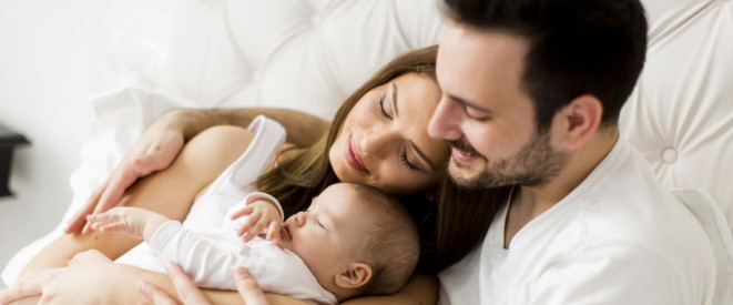 Vaterschaft anerkennen: Wichtig für unverheiratete Eltern. Ein junges Elternpaar hat sich mit ihrem Baby aneinander gekuschelt.