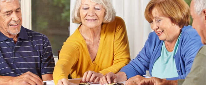 Betreutes Wohnen für Senioren: Die rechtlichen Grundlagen. Vier Senioren sitzen an einem Tisch und spielen Domino.