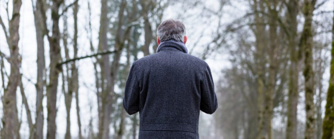 Elternunterhalt verwirkt: Wann Kinder nicht haften müssen. Ein Mann von hinten umgeben von kahlen Bäumen.