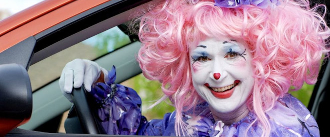 Maskiert Auto fahren: Greift das Vermummungsverbot? Eine als Clown verkleidete Frau sitzt hinter dem Steuer eines Autos.