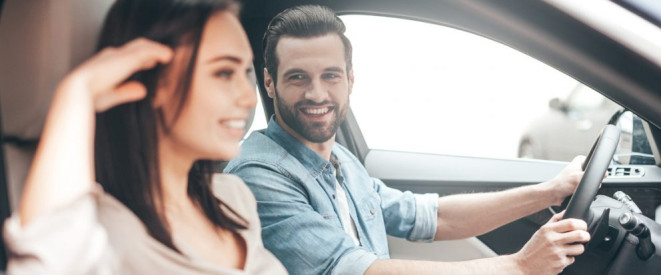 Beifahrer nicht angeschnallt: Wer zahlt das Bußgeld? Ein junges Paar sitzt im Auto. Der männliche Fahrer schaut die weibliche Beifahrerin an.