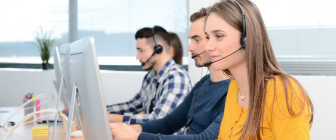 Frau und mehrere Männer in einem Callcenter vor dem Rechner