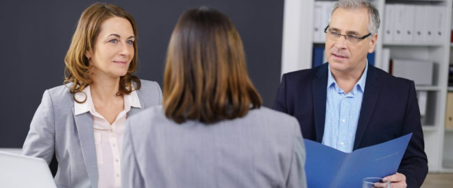 Im Büro: Zwei Frauen sprechen mit einem Mann, der eine blaue Mappe in der Hand hält