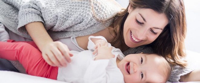 Lachende Mutter mit fröhlichem Baby