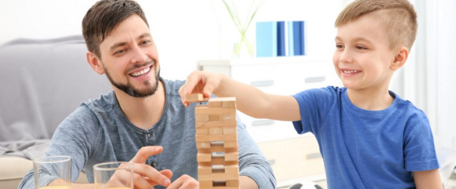 Mann und Junge bauen einen Turm aus Holzstäben