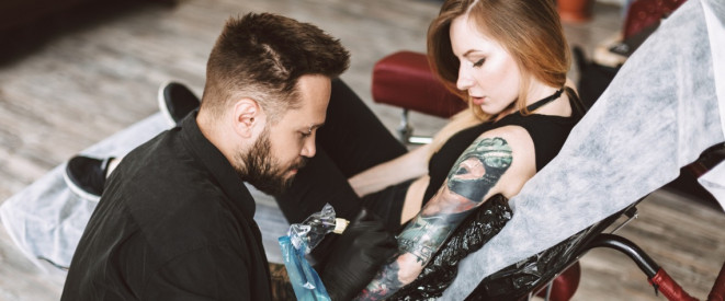 Tattoo Artist sticht Frau im Studio ein Tattoo auf dem Arm
