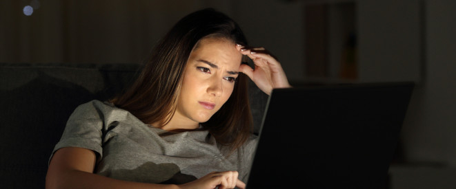 E-Mail-Konto gehackt: Spam-Mails vom eigenen Konto. Eine Frau sitzt entsetzt vor einem Bildschirm und schiebt sich entsetzt die Brille auf die Stirn.