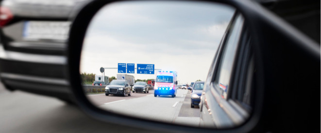 Autos Rettungswagen und Rettungswagen auf Autobahn im Autospiegel