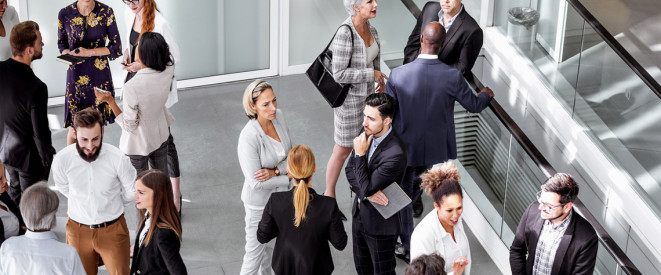 Mitarbeiter in einem Bürogebäude unterhalten sich in kleinen Gruppen