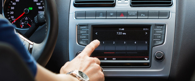 Nahaufnahme einer männlichen Hand, die das Radio in einem Auto bedient
