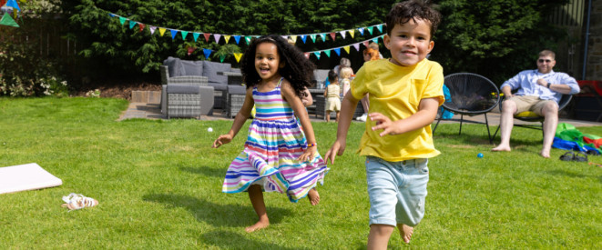 zwei Kinder rennen durch einen dekorierten Garten