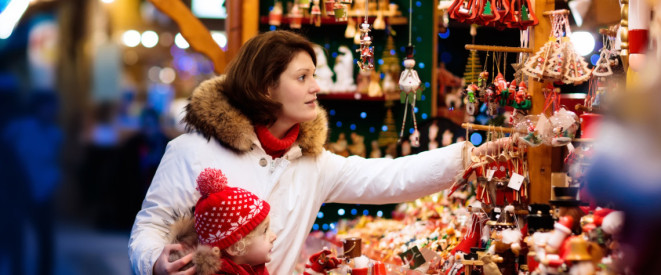 Frau mit Kind an einem Stand mit Weihnachtsdeko auf dem Weihnachtsmarkt