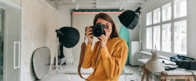 Frau in Studio macht Foto mit Kamera
