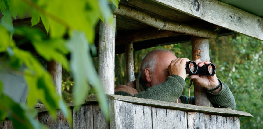 Jäger mit Fernglas auf Hochsitz