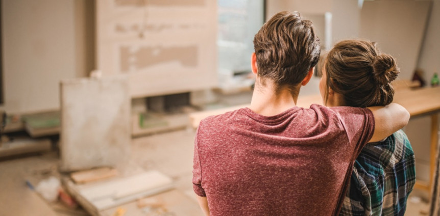 Junges Paar steht in neuer Wohnung auf Baustelle und schaut sie sich an