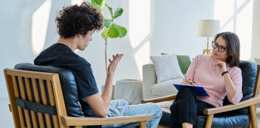 Psychotherapeutin und Patientin sitzen sich auf Stühlen gegenüber bei Therapiestunde