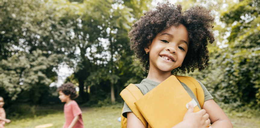 Mädchen mit Schulsachen lächelt in die Kamera