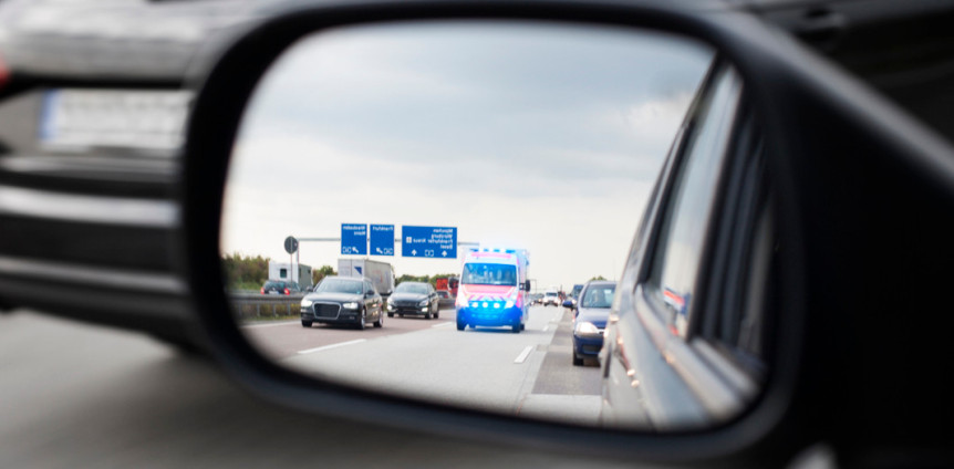 Autos Rettungswagen und Rettungswagen auf Autobahn im Autospiegel