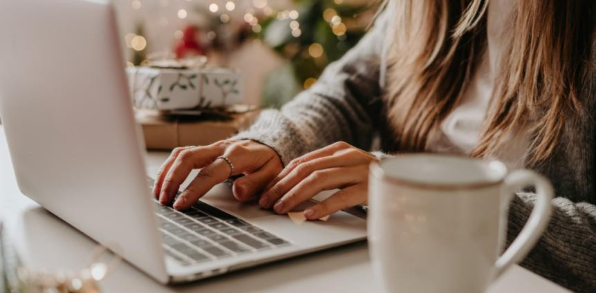 Eine Frau tippt in einen Rechner, eine Kaffeetasse steht auf dem Schreibtisch Eine Frau tippt in einen Rechner, eine Kaffeetasse steht auf dem Schreibtisch