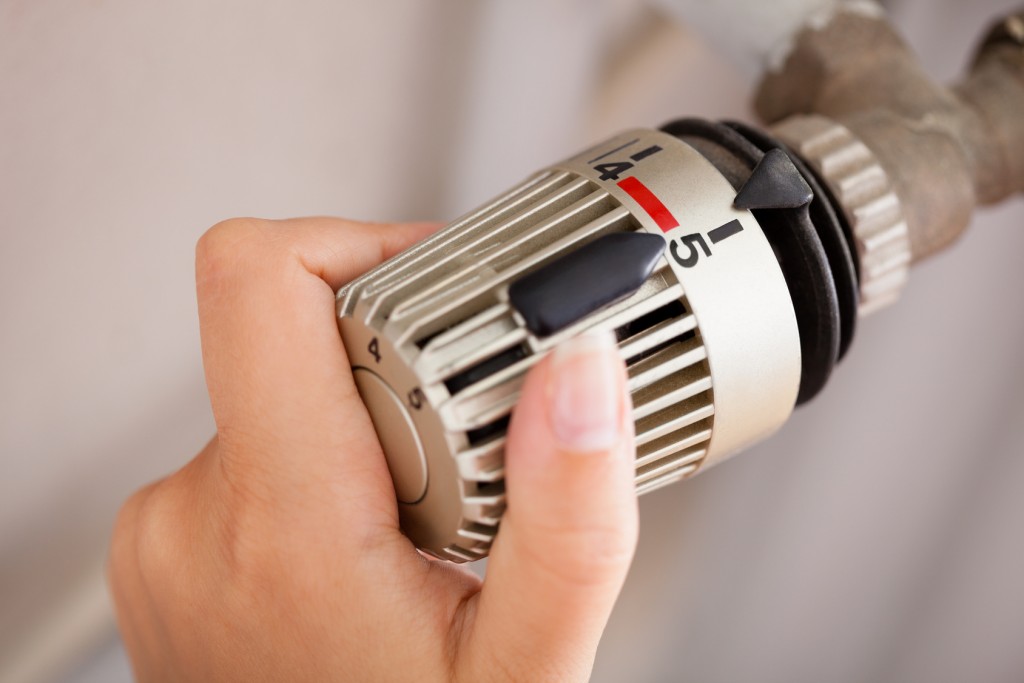 Mietminderung bei Heizungsausfall: Deine Rechte als Mieter Frau justiert das Thermostat.