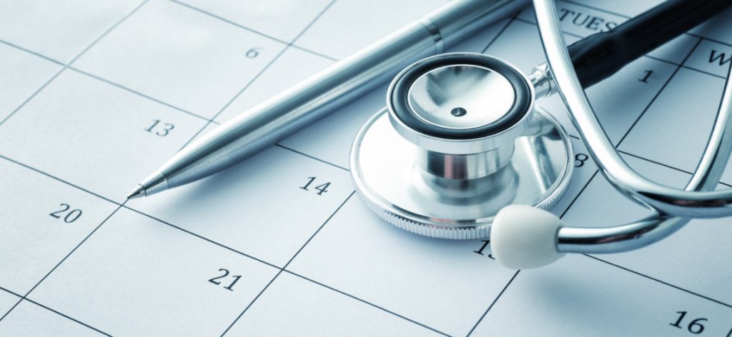 Stethoskop und Kugelschreiber liegen auf einem Kalenderblatt.