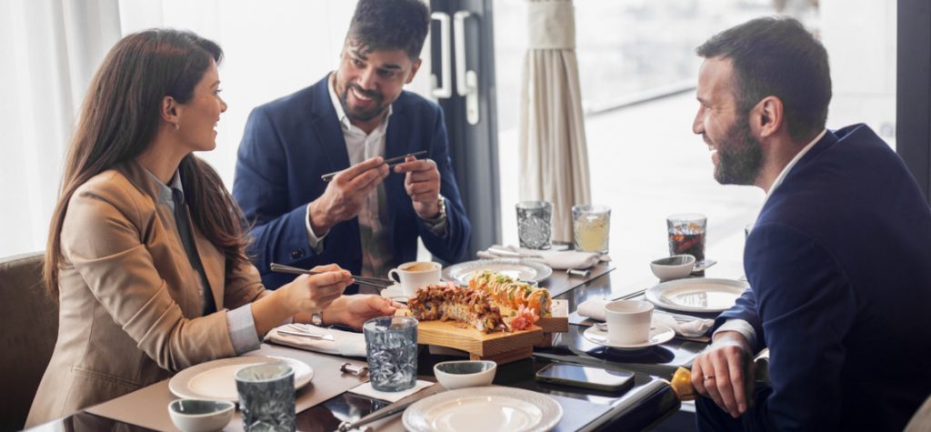 Drei Arbeitskollegen essen gemeinsam Sushi in einem Restaurant.