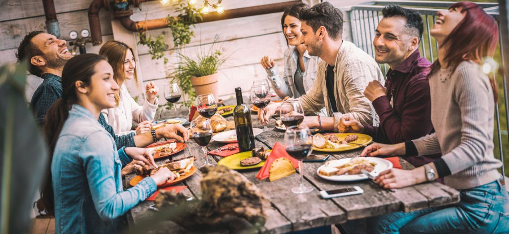 Junge Leute grillen draußen in der Sonne und haben Spaß