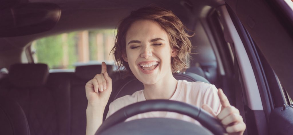 Junge Frau freut sich am Steuer eines Autos