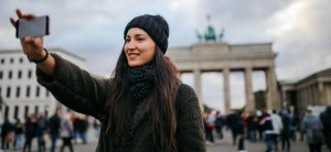 Frau macht Selfie von sich vor dem Brandenburger Tor