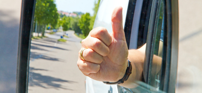 Autofahrer hält Faust mit Daumen hoch aus dem Autofenster