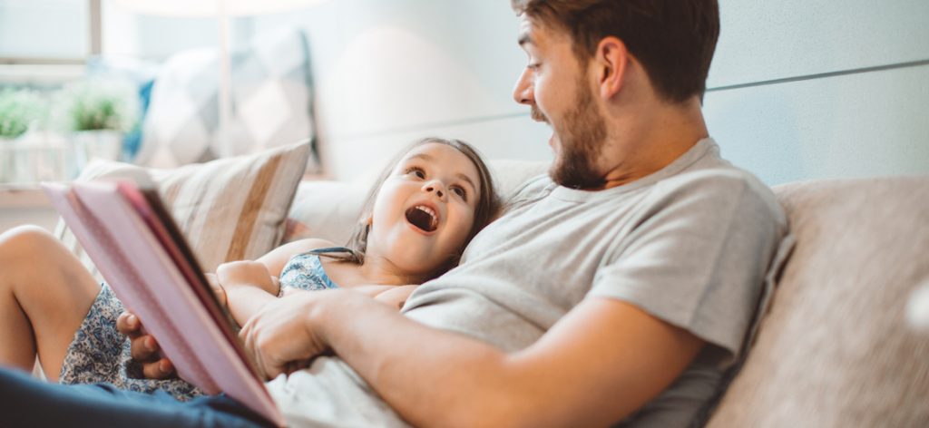 Vater und Tochter sitzen zusammen auf dem Sofa zu Hause und haben eine gute Zeit