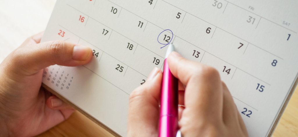 Personal kringelt mit einem Kugelschreiber den 12. Tag in einem Tischkalender ein.