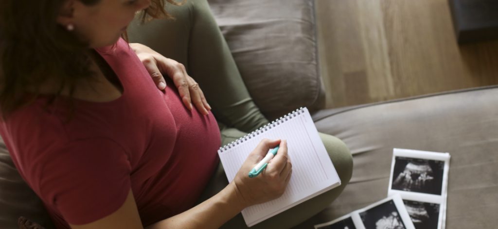 Eine schwangere Frau schreibt auf einem Block.
