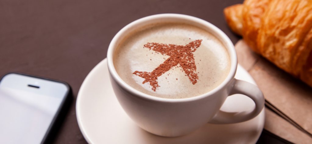 Eine Tasse Kaffee mit einem Flugzeug aus Streuseln auf dem Schaum.