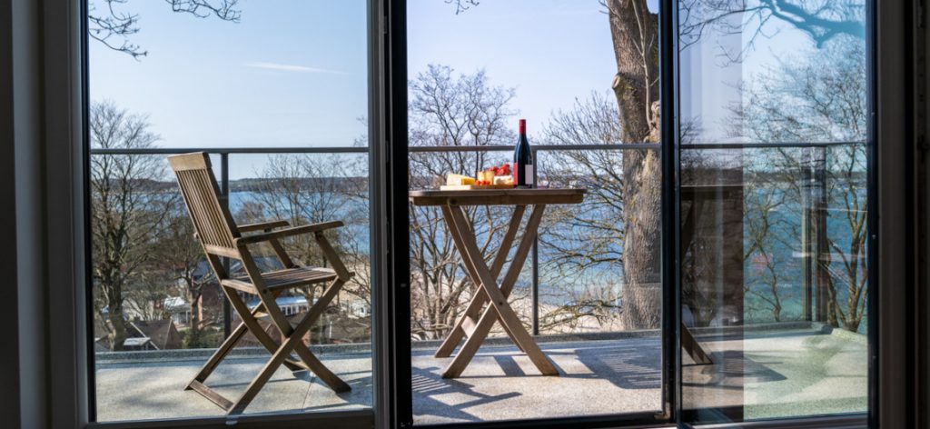 Blick aus dem Zimmer auf einen Balkon mit Tisch und Stuhl