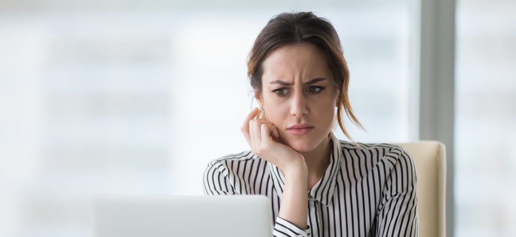 Junge Frau die skeptisch vor dem Laptop sitzt Ausbildung abbrechen: So gehst du richtig vor
