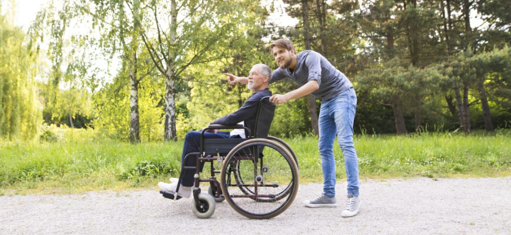 Sohn schiebt seinen im Rollstuhl sitzenden Vater Pflegeheim: Wer trägt die Kosten?