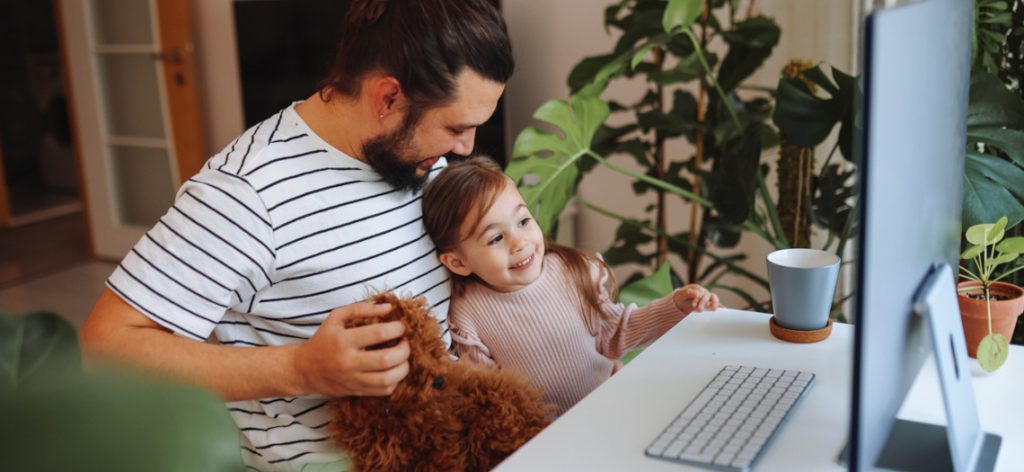 Vater und Tochter arbeiten zusammen im Homeoffice.