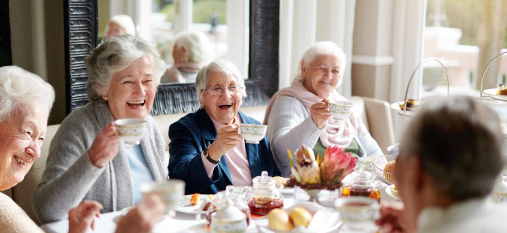 Eine Gruppe lachender Rentnerinnen beim Kaffeetrinken