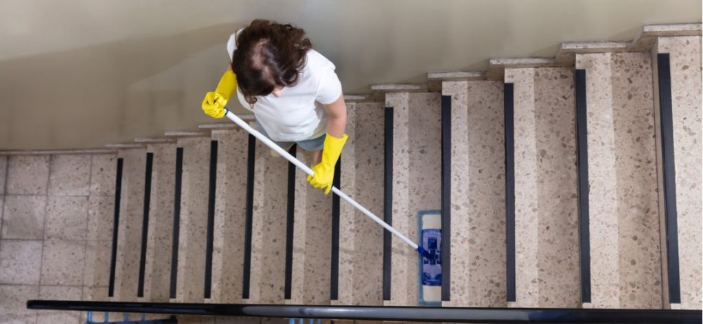 Aufsicht auf eine Frau, die eine Treppe in einem Treppenhaus wischt