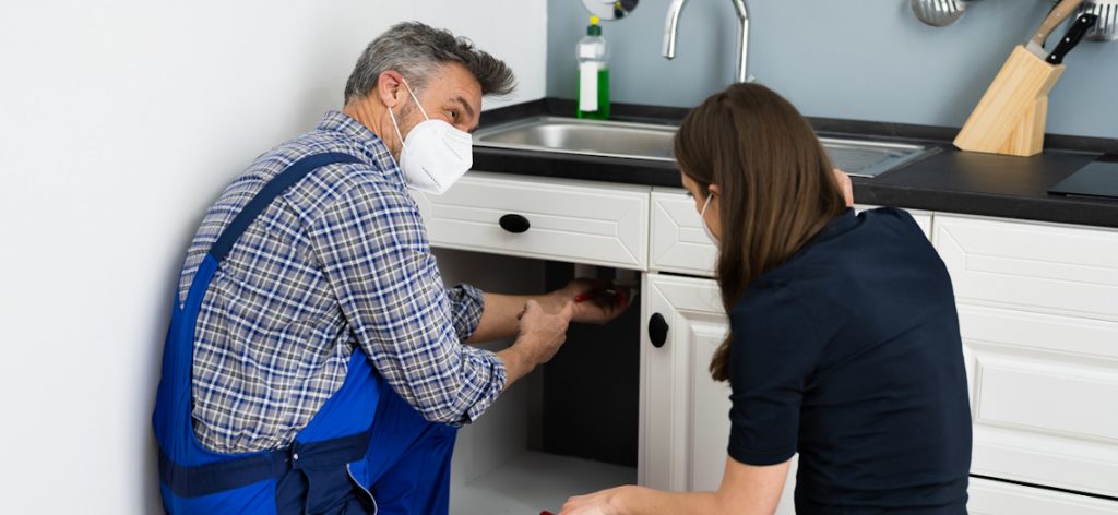 Handwerker repariert Abfluss in der Küche Handwerker repariert Abfluss in der Küche
