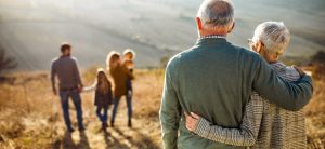 Rückenansicht von sich umarmenden Großeltern, die ihre Familie beobachten