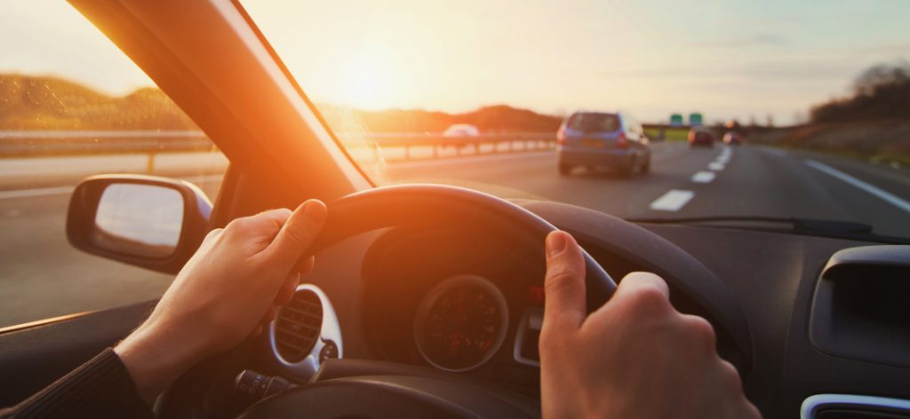 Autofahrer mit den Händen auf dem Lenkrad fährt auf der Autobahn.