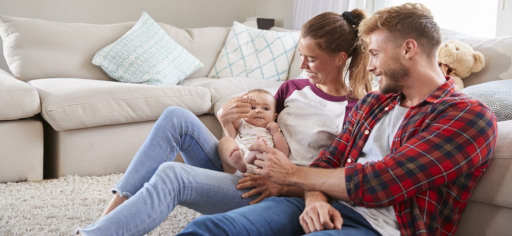 Junge Familie mit Baby sitzt auf dem Boden.